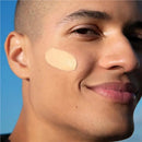 Close-up of a man's face with a patch on his cheek against a blue sky. Garnier BB Cream All In One Perfector Anti-Age Medium SPF 15 