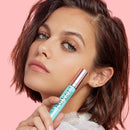 Woman applying makeup with a brush against a pink background - L'Oreal Paris Lash Paradise Waterproof Mascara Black