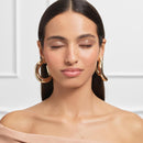 Woman wearing gold hoop earrings with a neutral background