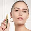 Woman holding a gold mascara tube with a blurred background