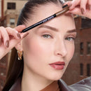 Woman using a brow pencil to groom her eyebrows with a blurred background - Maybelline Brow Shaper Eyebrow Pencil  Brown