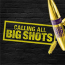 Maybelline New York Colossal Big Shot mascara shown with a gold bullet-shaped tube, a small gold brush, and a yellow graphic reading 'CALLING ALL BIG SHOTS' on a black brick wall background. Maybelline Colossal Big Shot Volumizing Mascara - Blackest Black