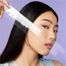 Woman with a clear face mask being applied to her face against a purple background