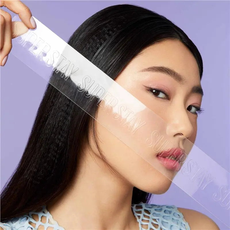 Woman with a clear face mask being applied to her face against a purple background