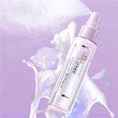 Maybelline Super Stay Double Wear spray bottle on a purple background with white floral elements.