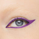Close-up of a human eye with dramatic purple eyeshadow and a sharp winged eyeliner look on light skin. Maybelline Tattoo Gel Pencil Eyeliner Purple Pop