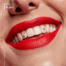 NYX Smooth Whip Matte Lip Cream 12 Icing on Top - Close-up of a smiling person's mouth wearing bright red lipstick and small rhinestone nail wraps, with part of the nose and skin visible. Text in the corner reads PLAY and vertical text reads PROFESSIONAL MAKEUP.