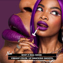 Woman applying purple lipstick with a product labeled 'Whip It Real Good' on a purple background.